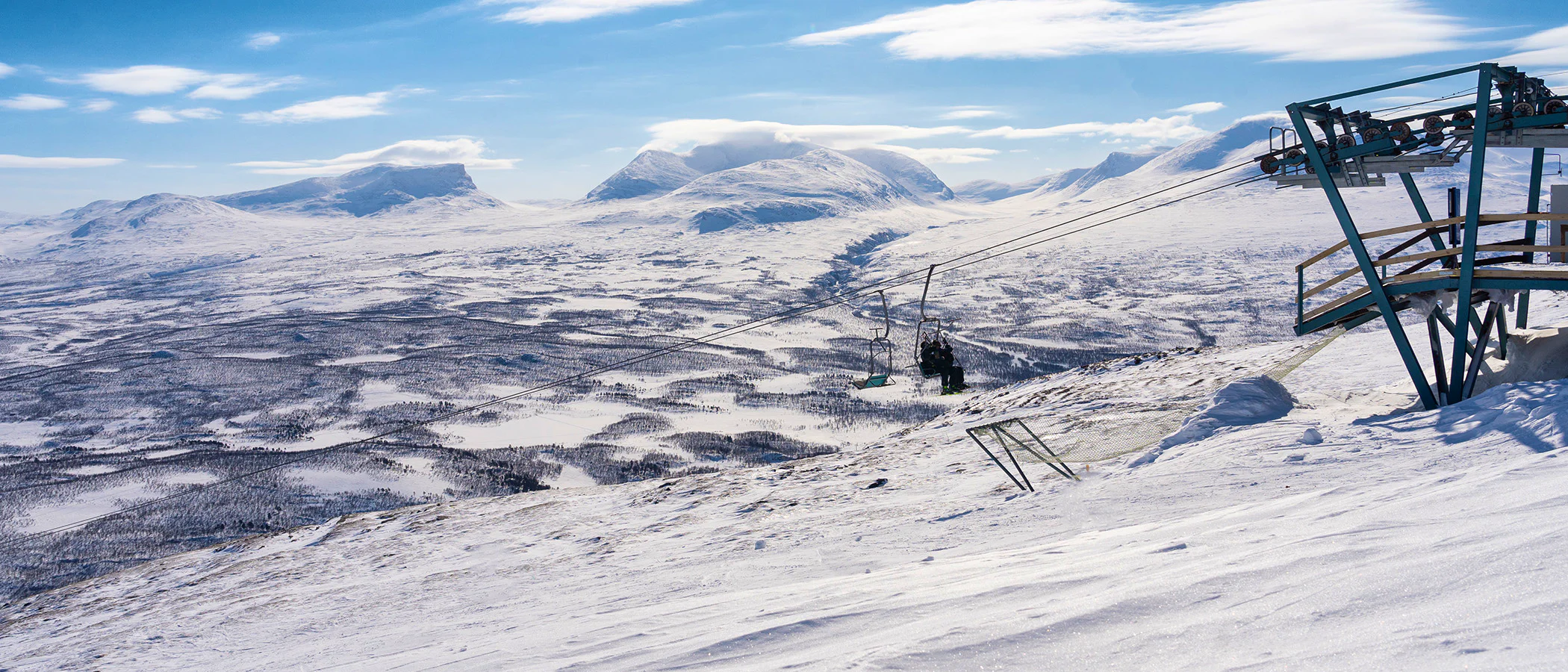 Two people in a sit lift in Abisko with the mountain view in the winter time.