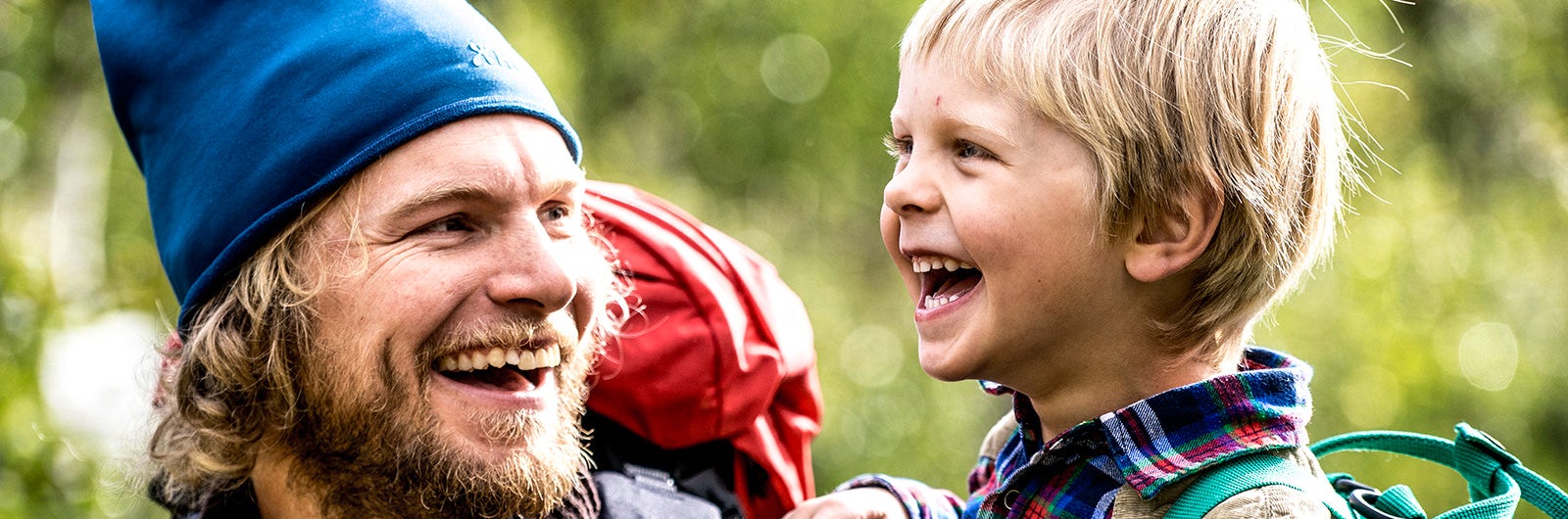 A father and son laughing in the woods.