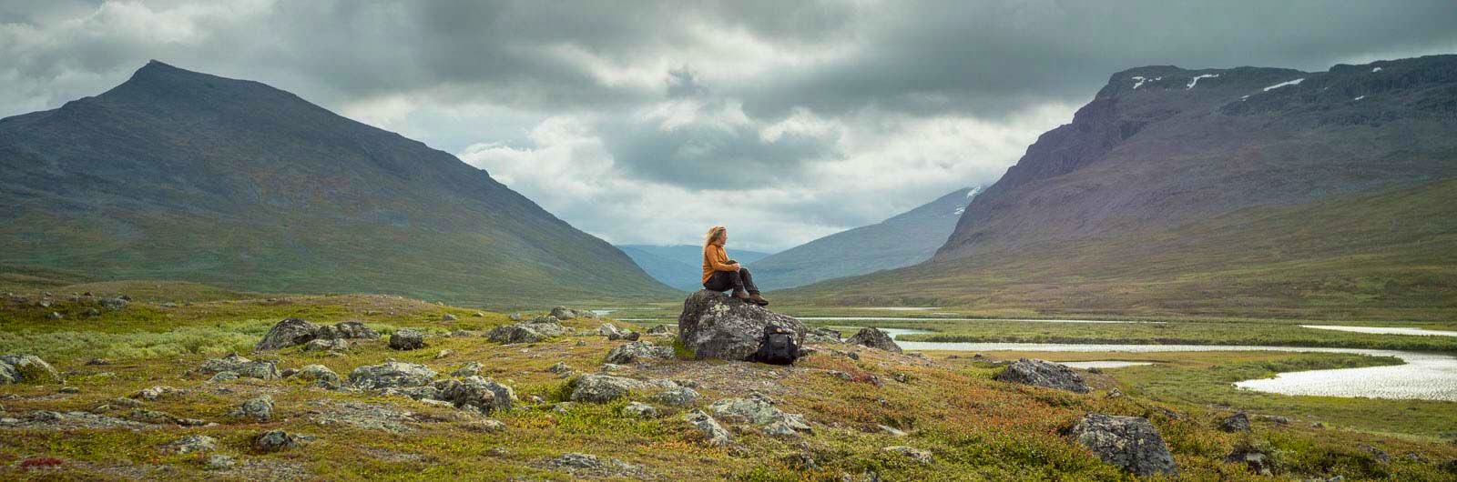 A woman sitting on a rock in the mountains.