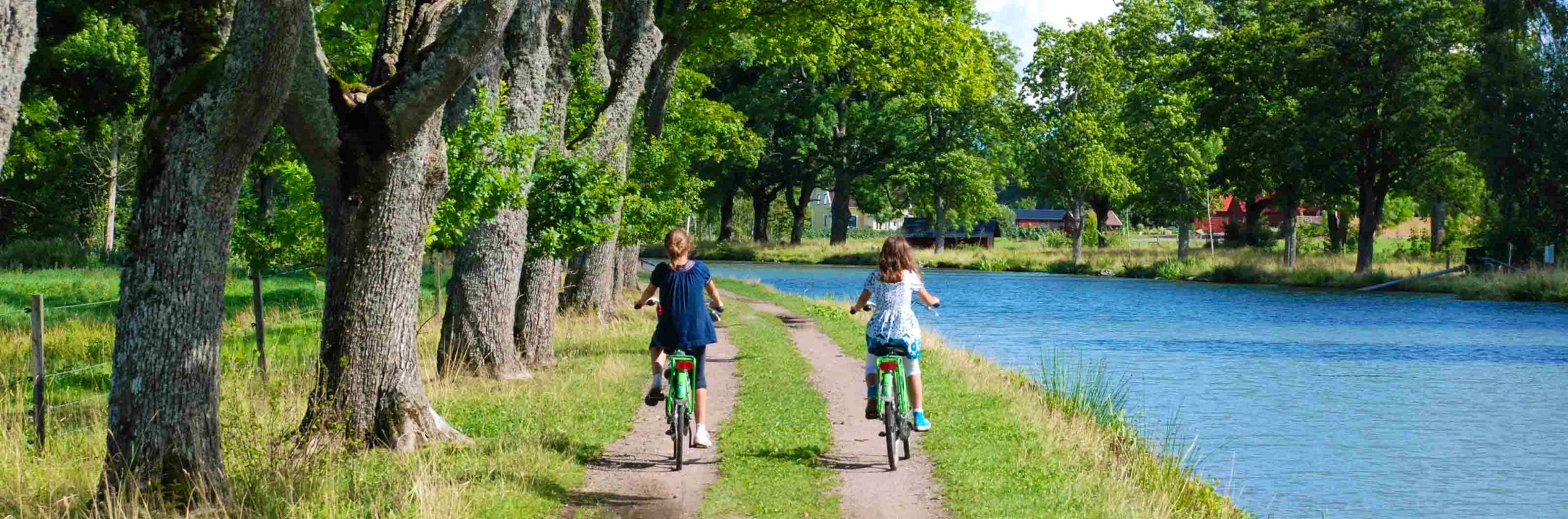 Two people cycling along the river Göta kanal.