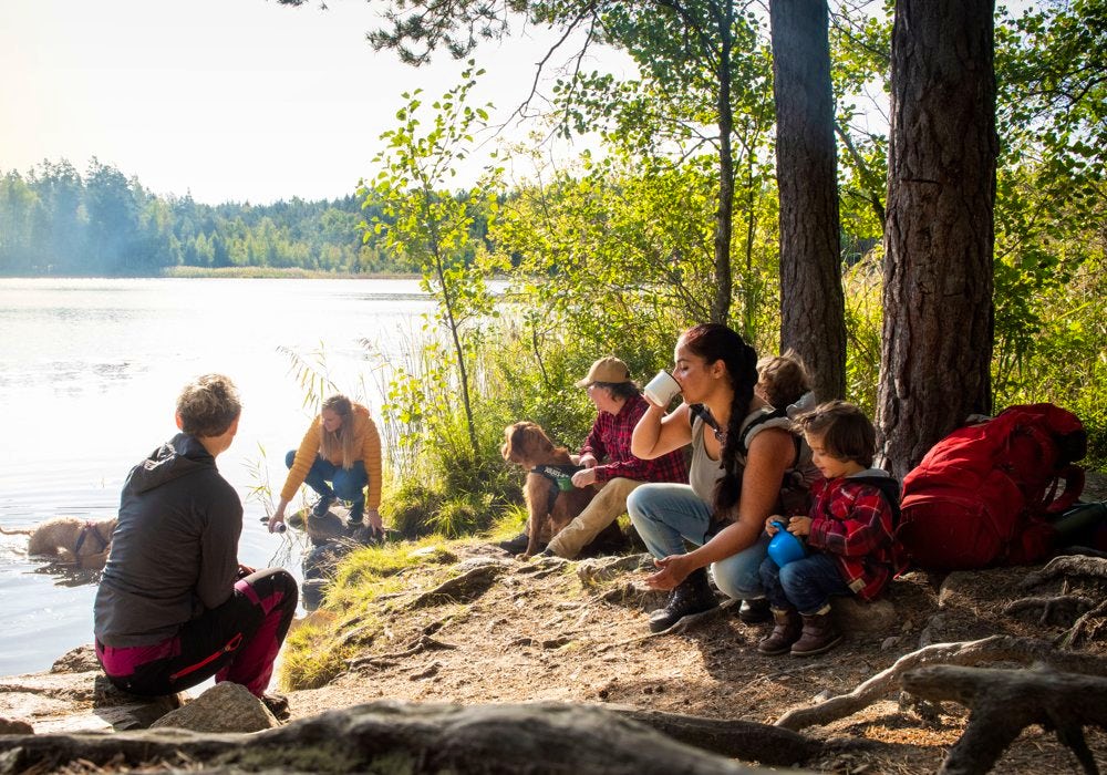A group of people sitting on the shore of a lake.