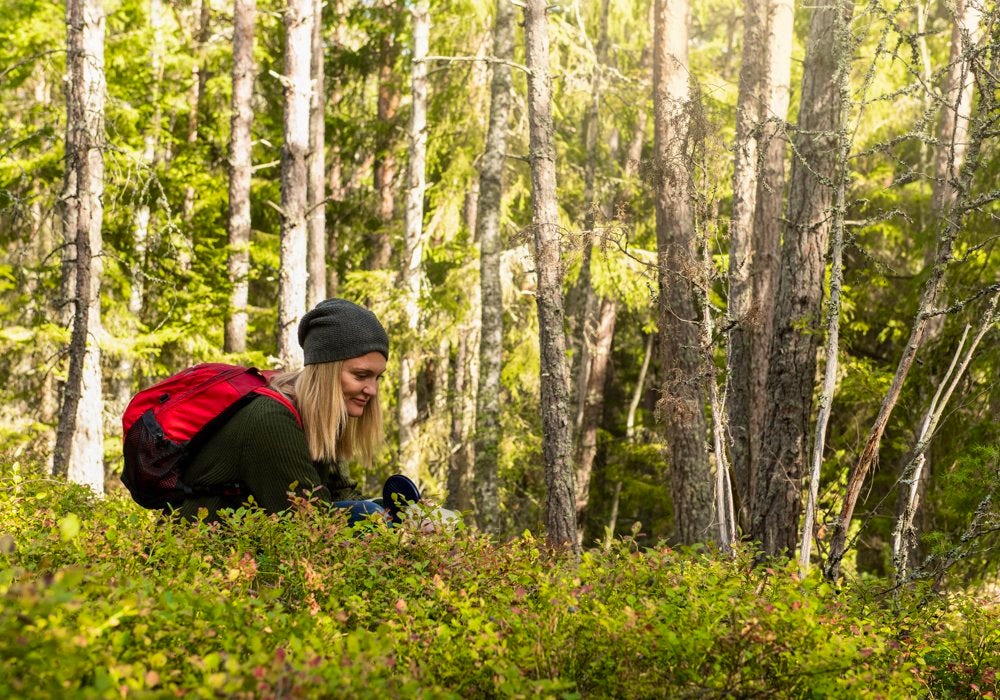 A woman hiking through the woods with a backpack.