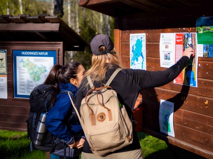 Two people pointing at an information board.