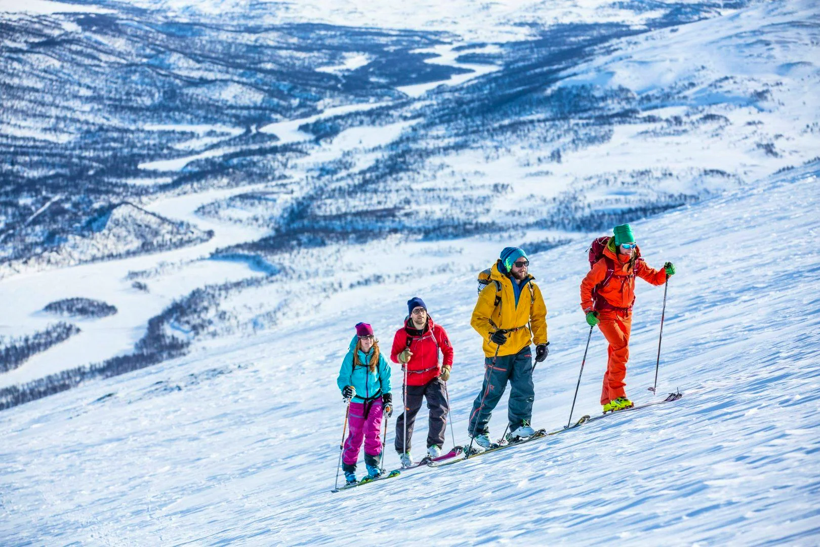Four skiers climbing a snowy mountain slope with panoramic views.