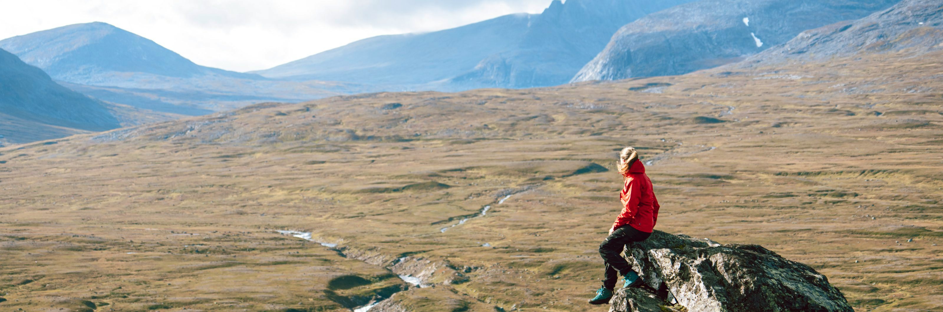 A woman sitting on a rock in the mountains. 