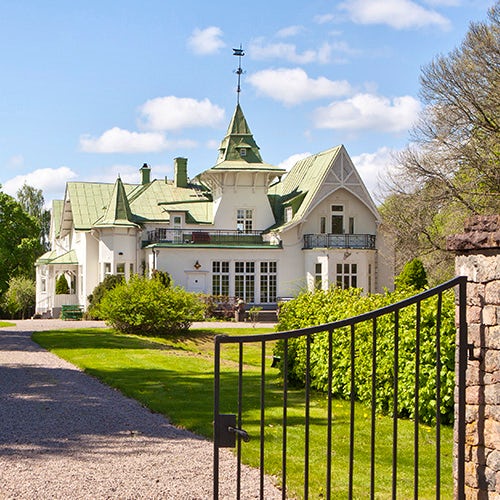 A white villa with a green tin roof and a tower.