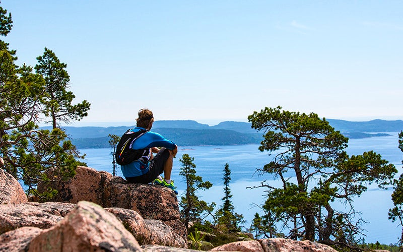 Man sits on a mountain, gazing out over the beautiful view.
