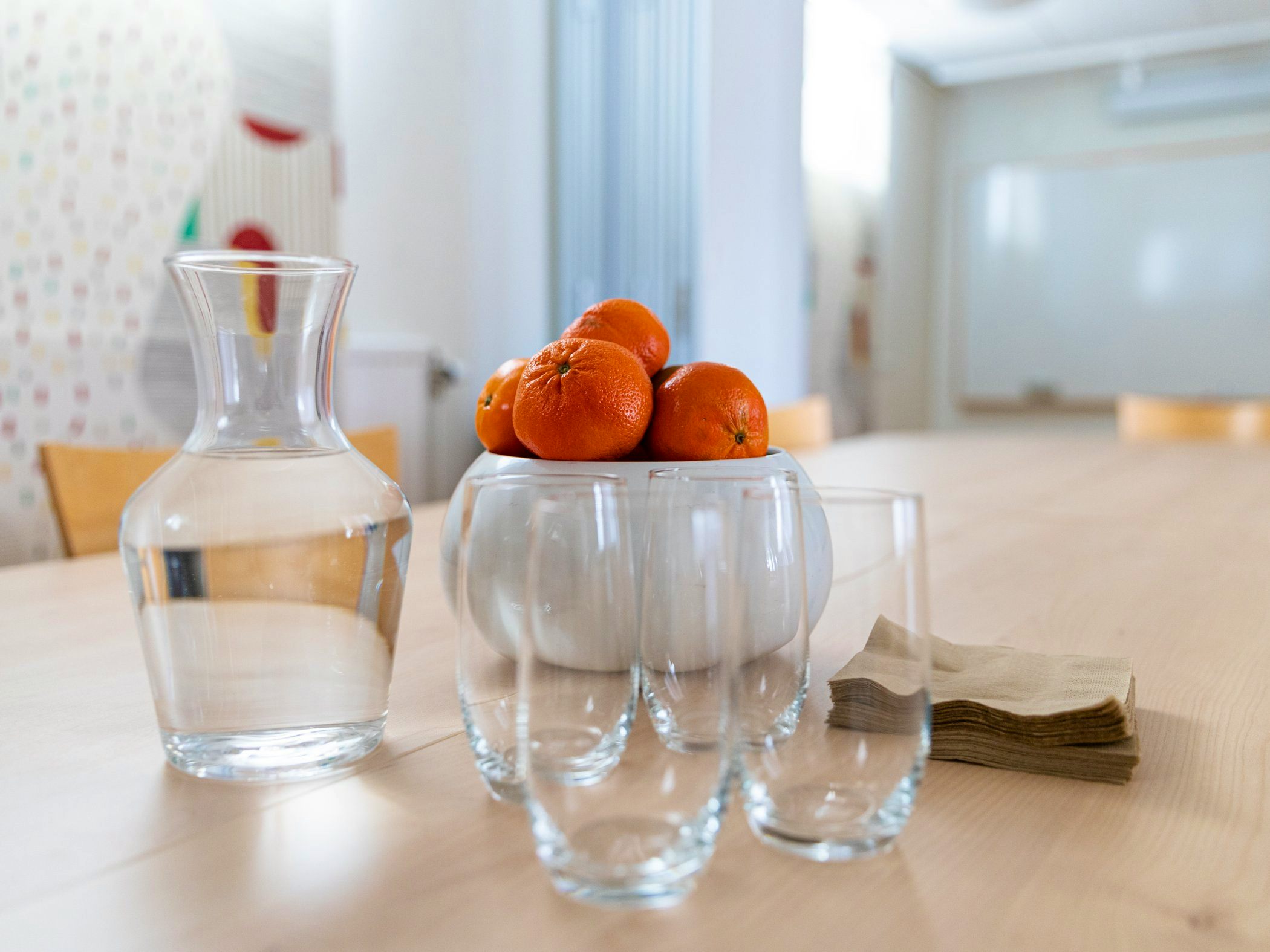 A bowl of oranges sitting on top of a wooden table.