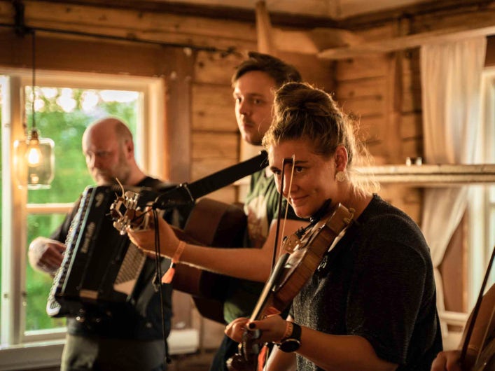 STF Saltoluokta Fjällstation tre personer spelar instrument.