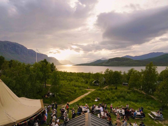 STF Saltoluokta Fjällstation festivaltält framför utsikt mot vatten och fjäll.