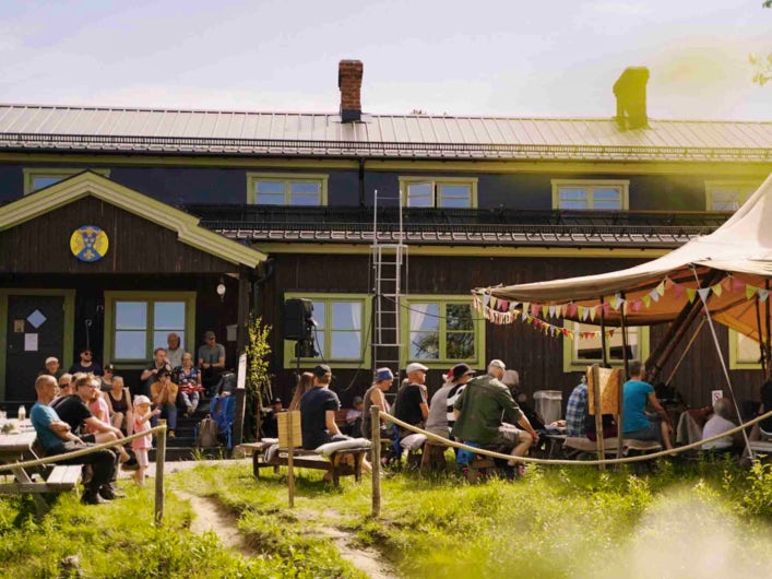 STF Saltoluokta Fjällstation med folk utanför på bänkar.
