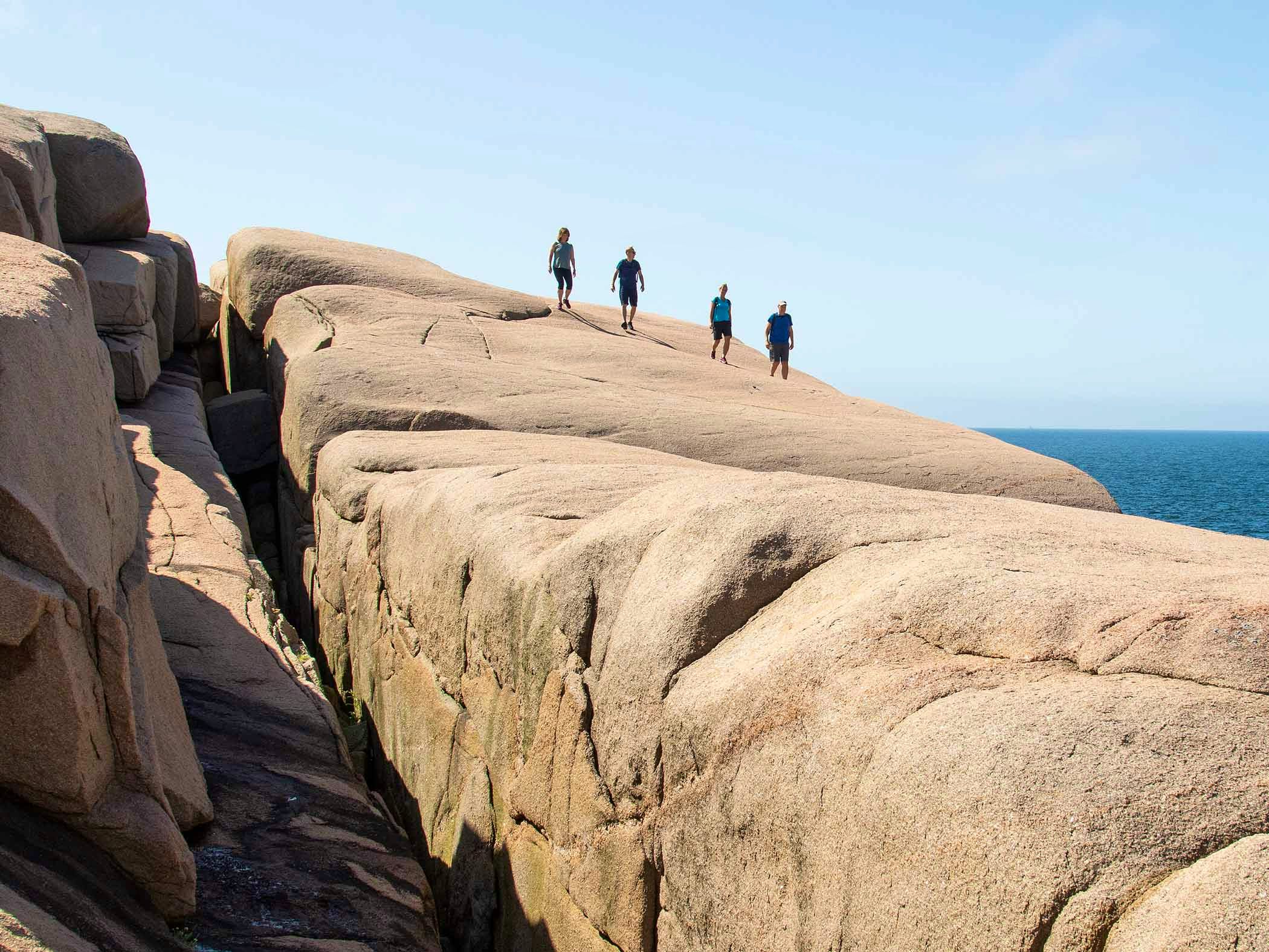 Four persons trekking on cliffs in west Sweden.