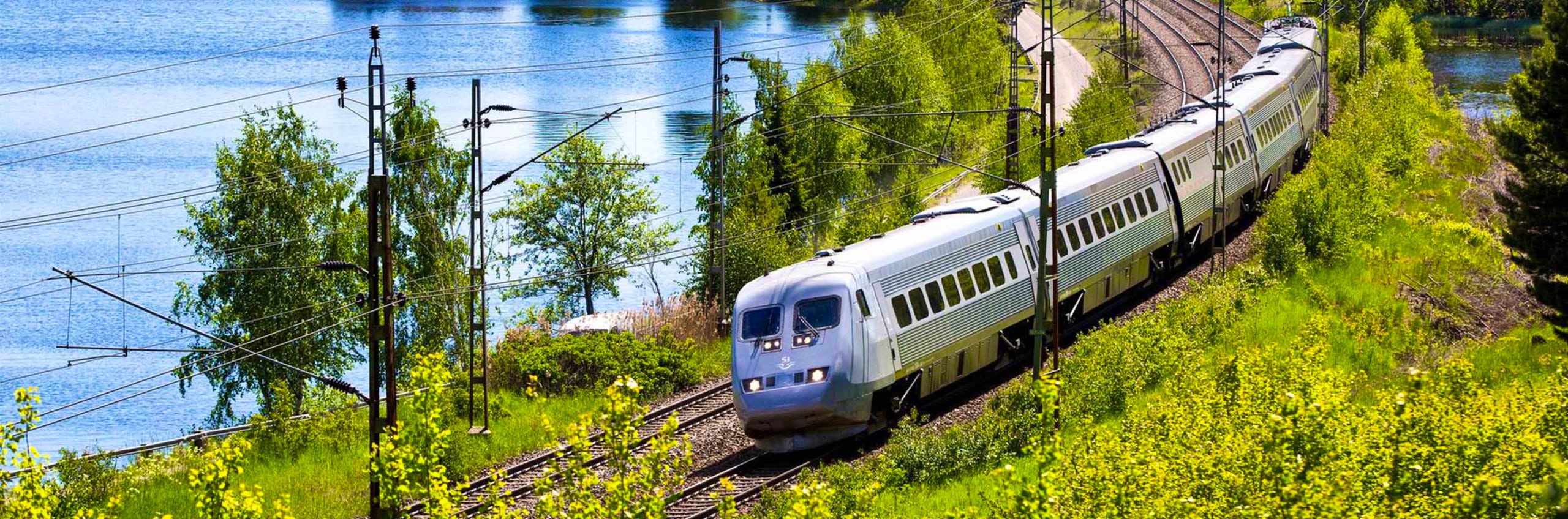 A train on the tracks near a lake.