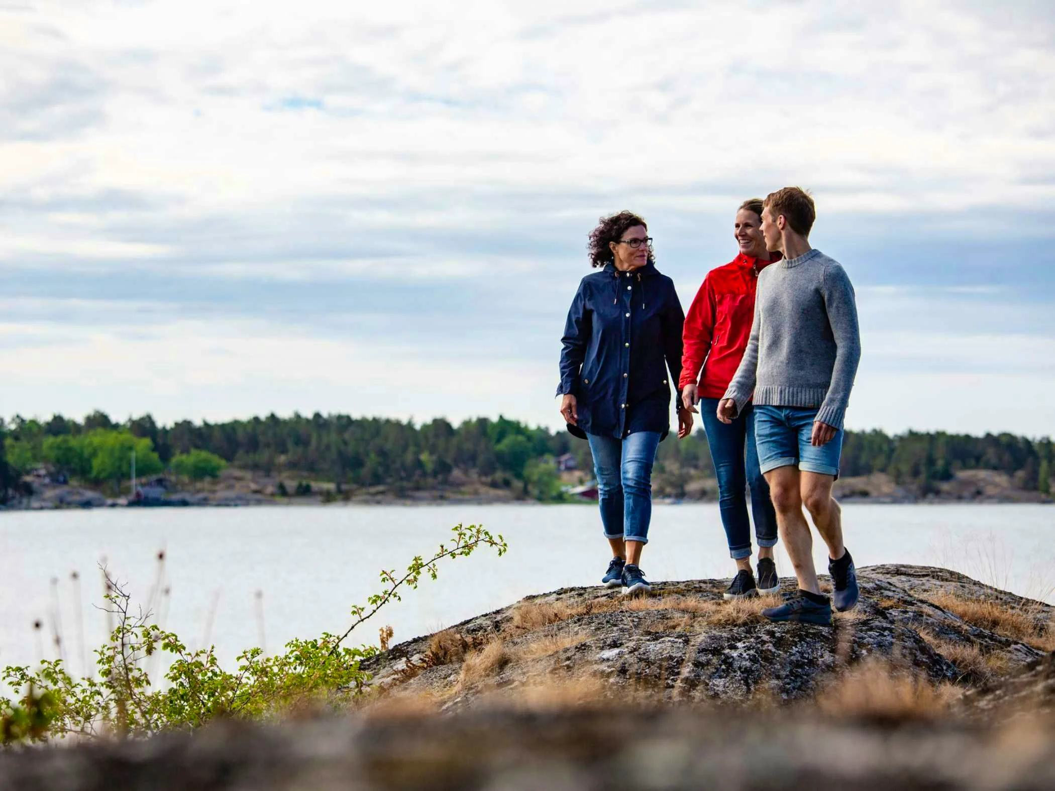 Three persons standing on a cliff by the sea in Stockholm Archipelago.
