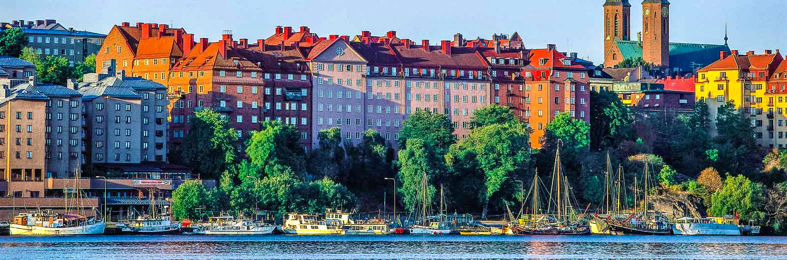 Colorful apartment buildings along waterfront with boats in Stockholm.