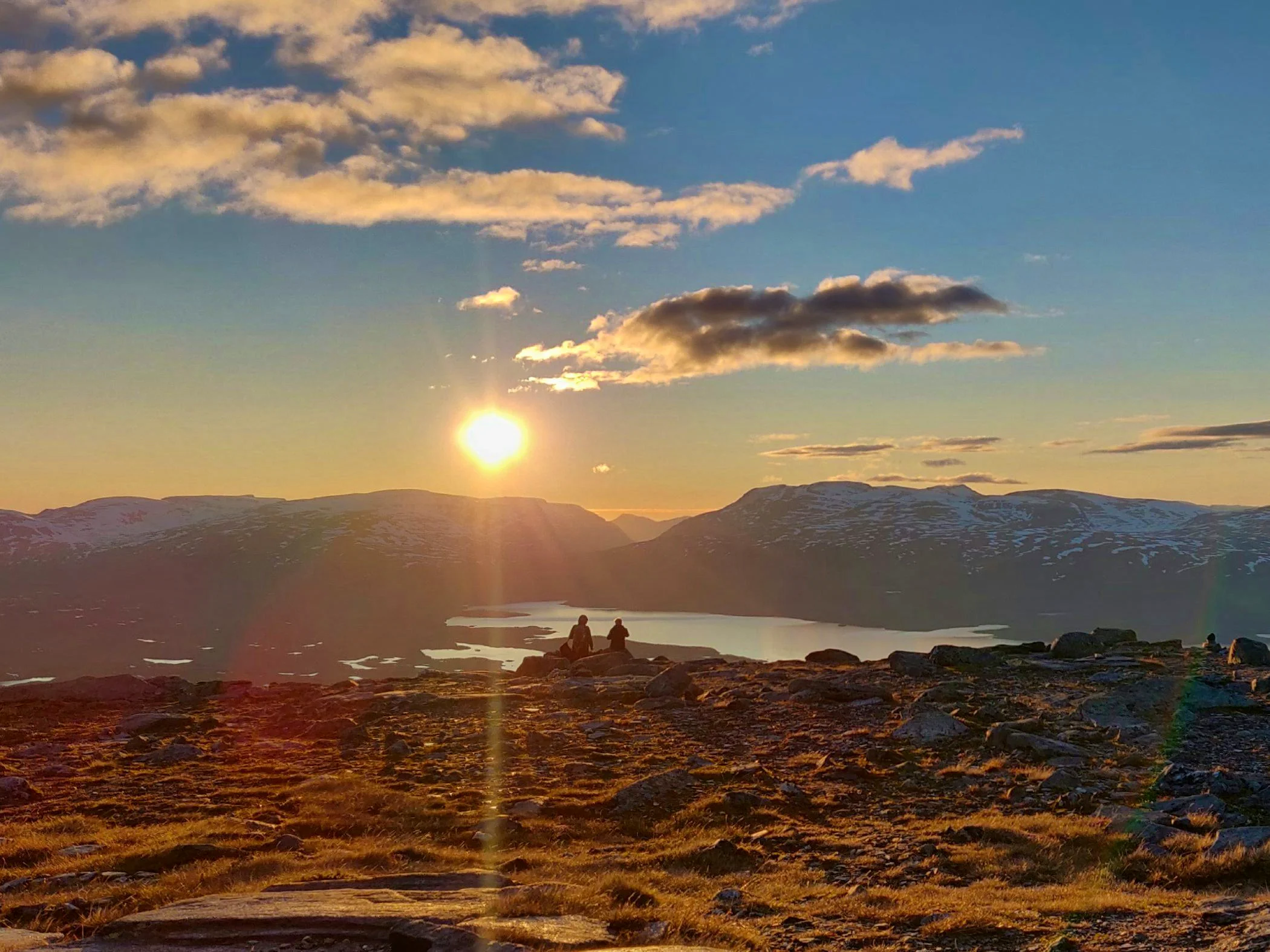 Two people are watching the sunset on a mountain in a beautiful mountain landscape.