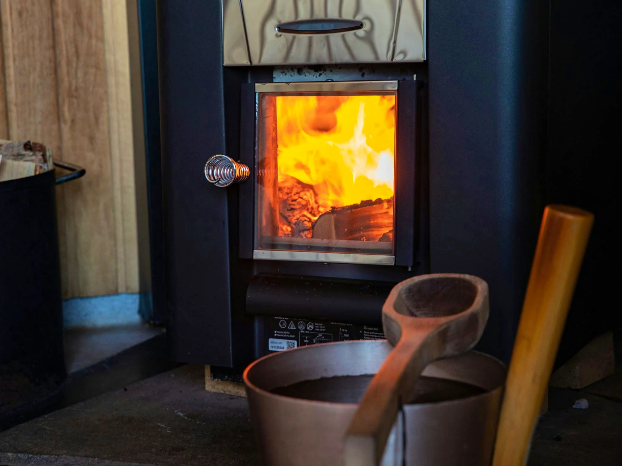 Close-up of a sauna stove with fire burning inside.