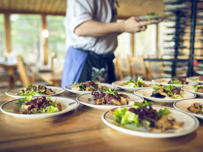 A man standing in front of a table filled with plates of food.