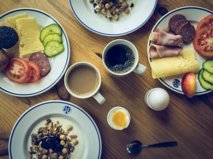 A table topped with plates of food and cups of coffee.