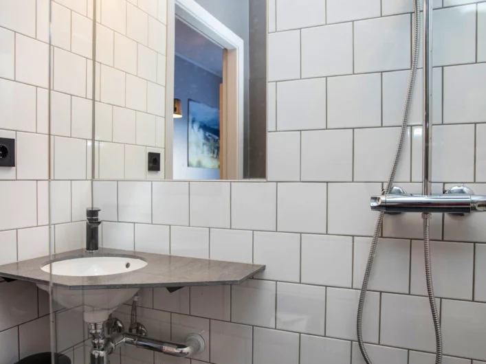 A bathroom with a sink and a shower head.