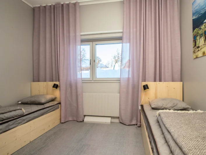 A bedroom with two beds and a window.
