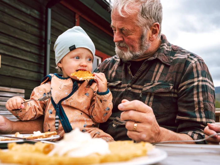 A man and a child eating pizza at a table.