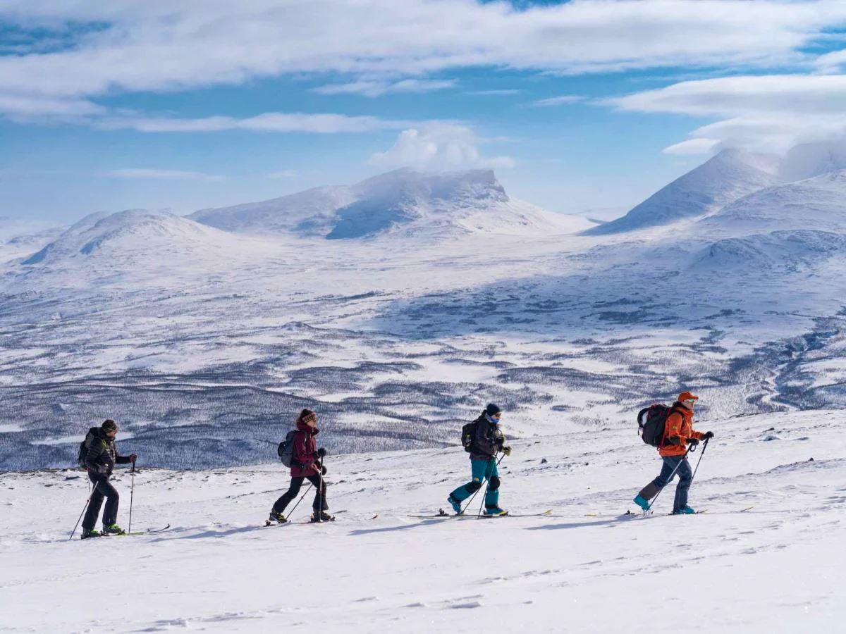Ski tourers crossing a snowy mountain landscape.