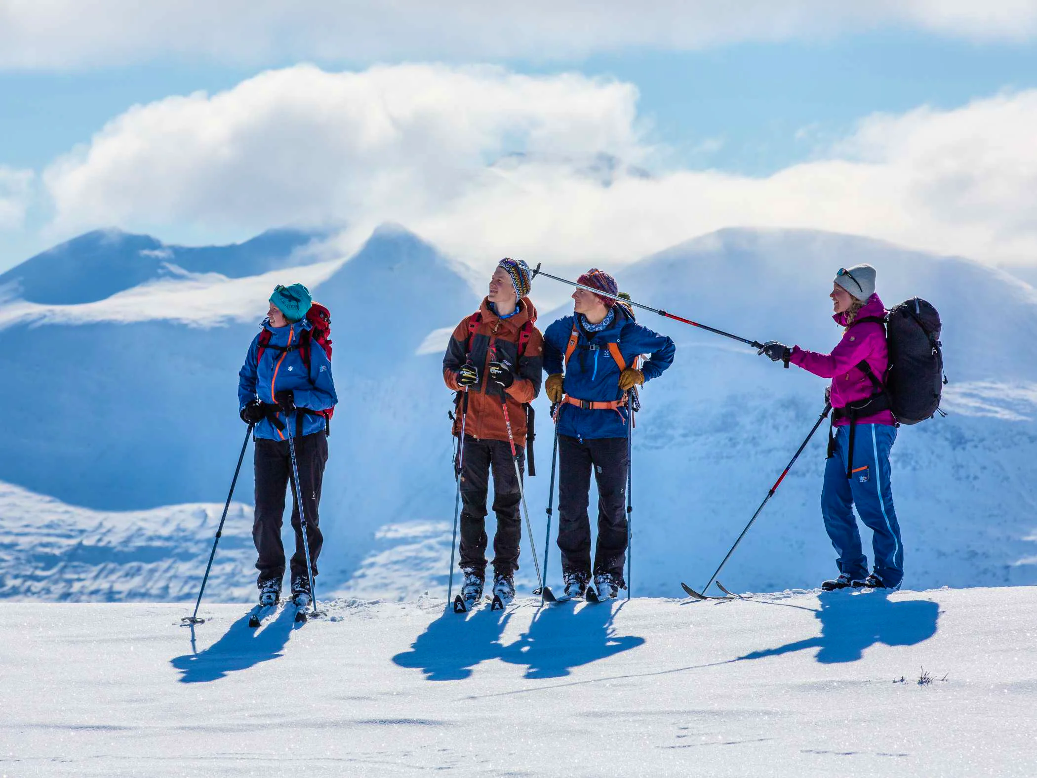 Group on a guided ski touring trip in the mountains with snow-covered peaks in the background.