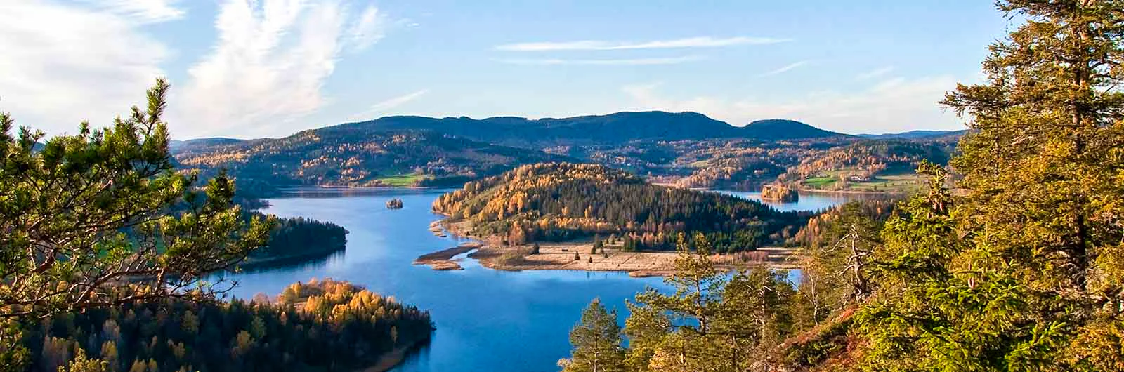 View over a lake and forested hills in autumn colours.