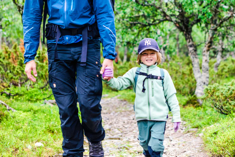 A man and boy walking hand in hand in the forest.