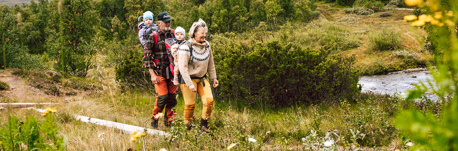 An older woman and man hiking with two children on a boardwalk in the mountains.