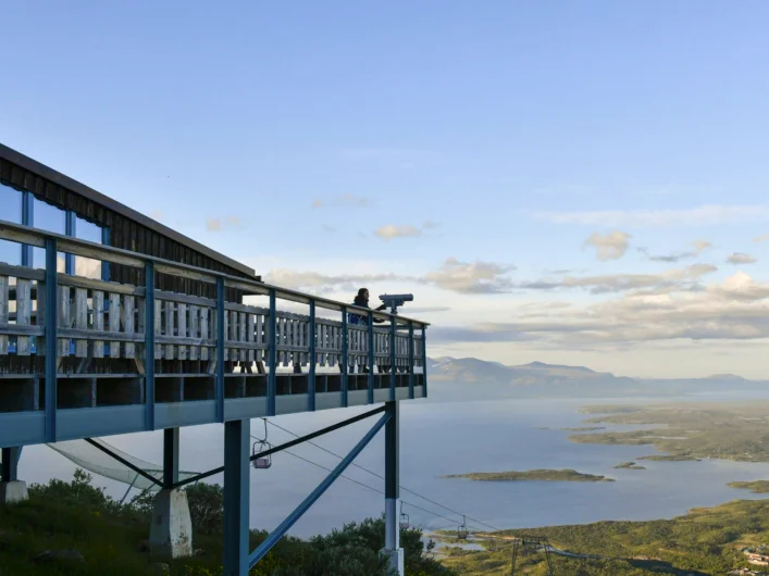 A person standing on a balcony overlooking a lake at Aurora Sky Station.