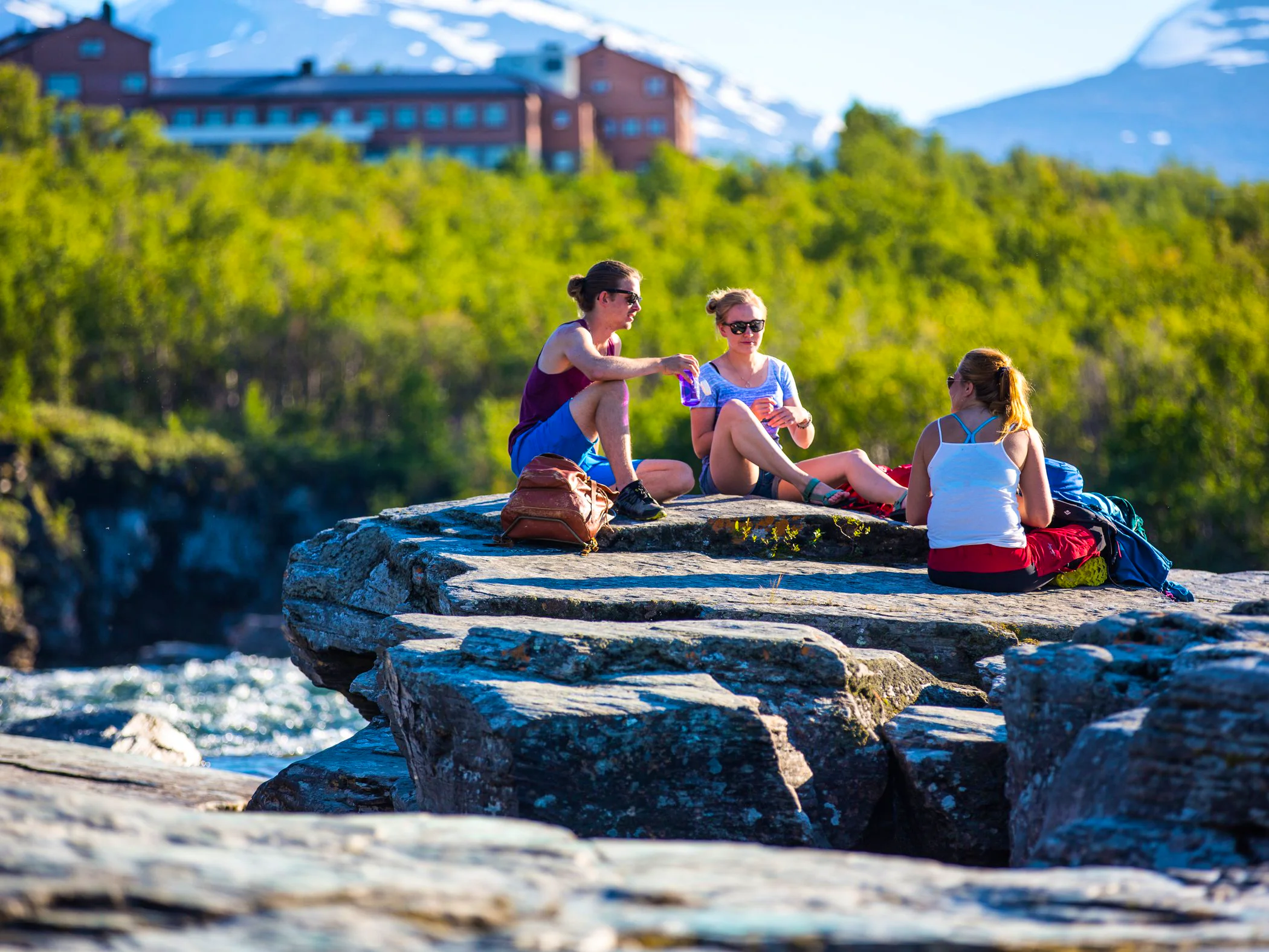 En grupp barn som sitter på en sten vid en flod.