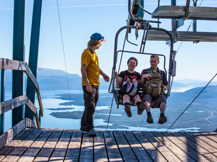 Two people sitting on a chair lift to Aurora Sky Station.